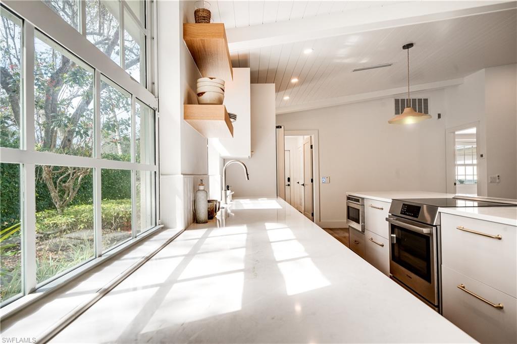 3695 El Segundo Court Naples, FL 34109 - Photo 14 of 37 Kitchen featuring hanging light fixtures, stainless steel appliances, white cabinetry, and light countertops