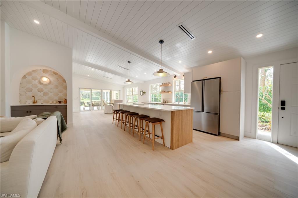 3695 El Segundo Court Naples, FL 34109 - Photo 37 of 37 Kitchen with lofted ceiling with beams, open floor plan, freestanding refrigerator, a center island, and pendant lighting