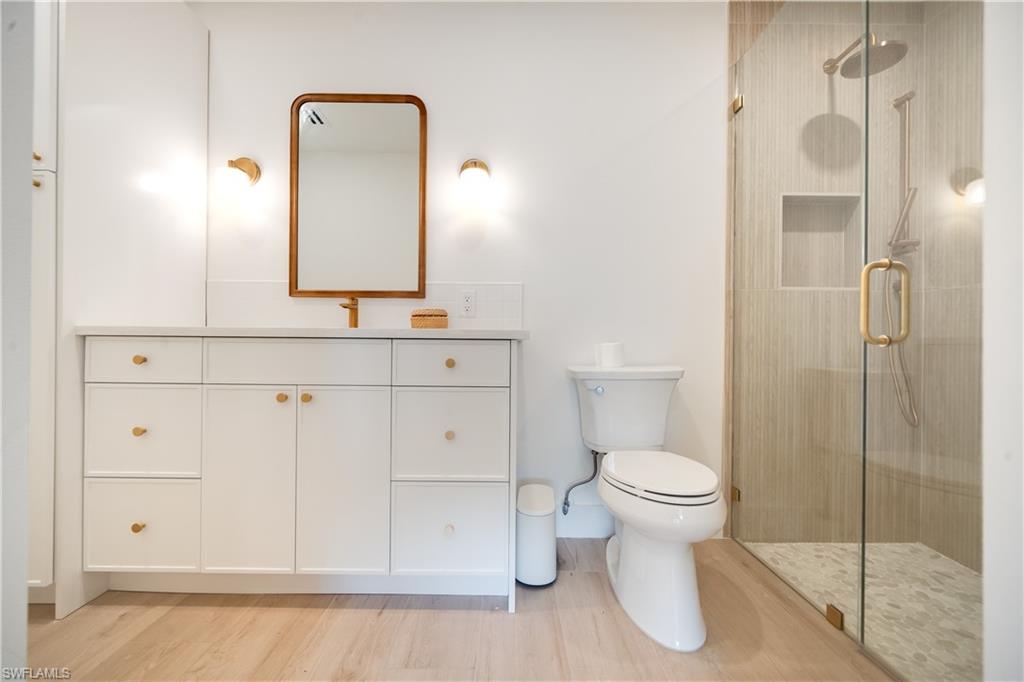 3695 El Segundo Court Naples, FL 34109 - Photo 4 of 37 Full bath featuring toilet, a stall shower, wood finished floors, and vanity