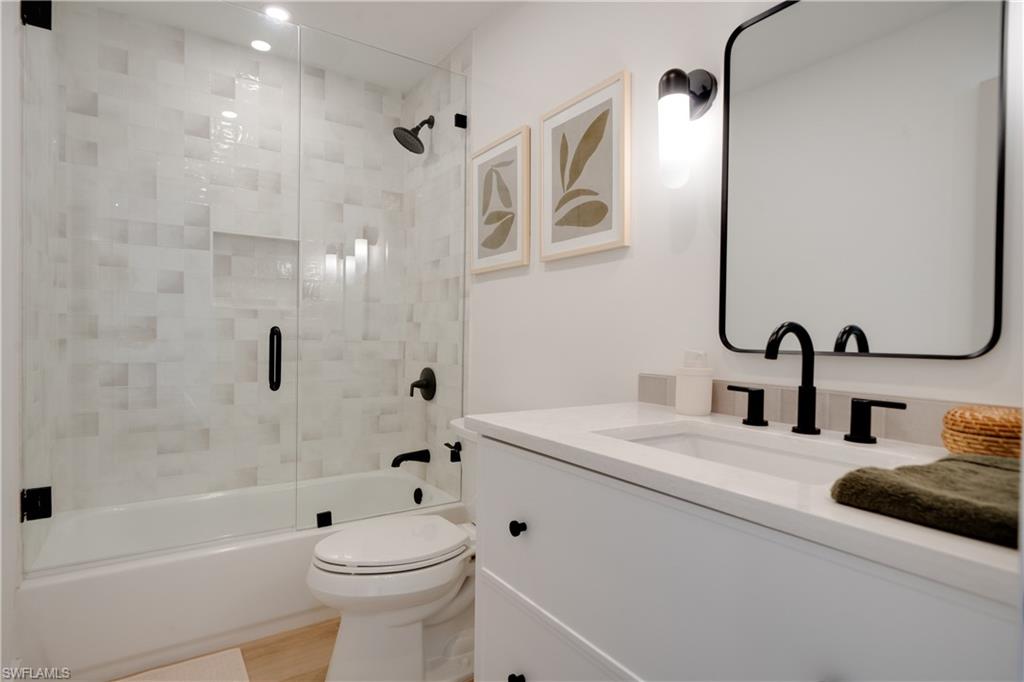 3695 El Segundo Court Naples, FL 34109 - Photo 6 of 37 Bathroom with toilet, bath / shower combo with glass door, wood finished floors, and vanity