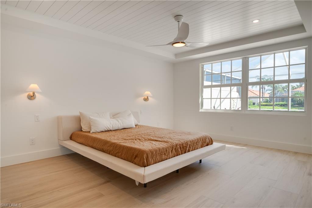 3695 El Segundo Court Naples, FL 34109 - Photo 8 of 37 Bedroom featuring light wood finished floors, a tray ceiling, wooden ceiling, and baseboards