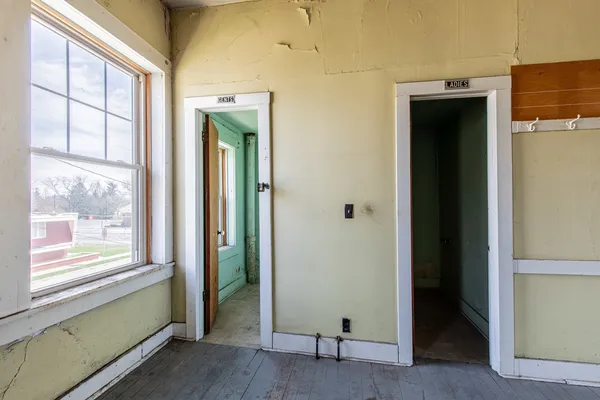a view of an empty room with wooden floor and windows