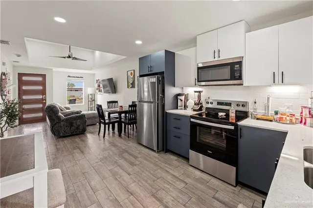 a kitchen with kitchen island a counter top space a sink stainless steel appliances and cabinets