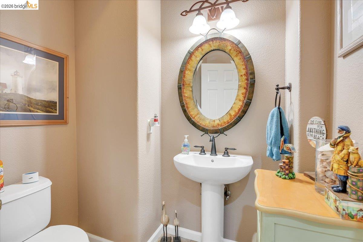 158 Rock Ridge Lane Copperopolis, CA 95228 - Photo 26 of 72 Pedestal sink with dark bronze faucet, framed oval mirror, and wall-mounted light fixture