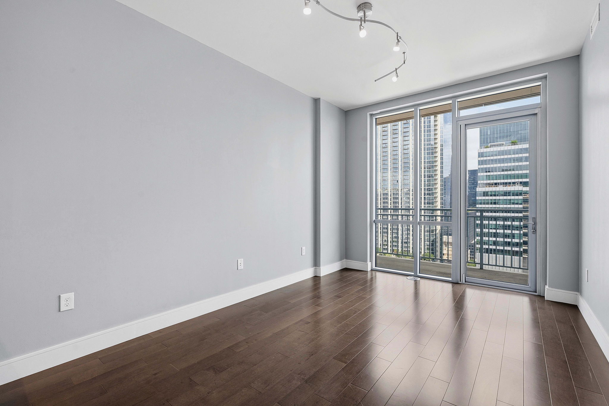 222 West Avenue, Unit 2207 Austin, TX 78701 - Photo 8 of 30 Expansive windows with balcony access, dark wood-finish flooring, light gray wall tones, white baseboards, and track lighting