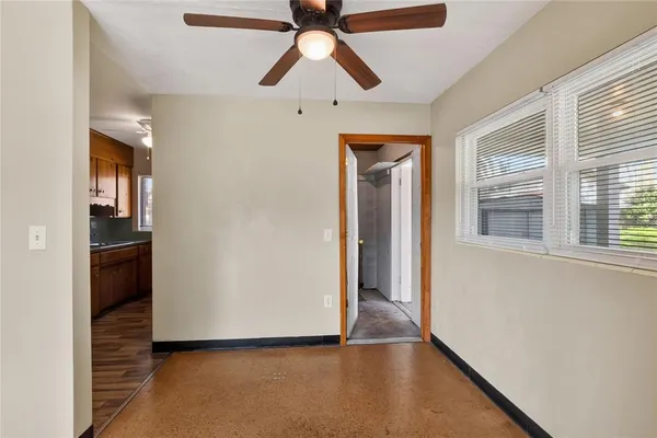 a view of an empty room with a window and a kitchen