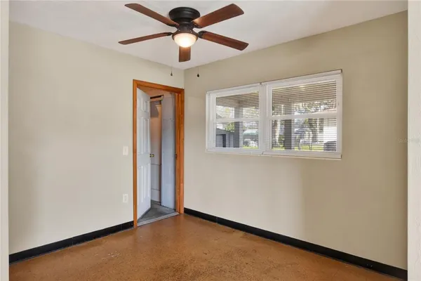 an empty room with windows and fan