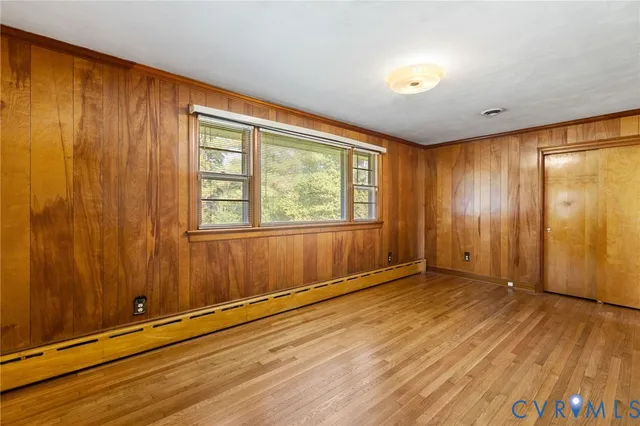 an empty room with wooden floor and windows with curtains