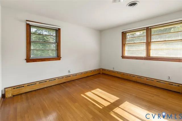 a view of an empty room with a window and wooden floor