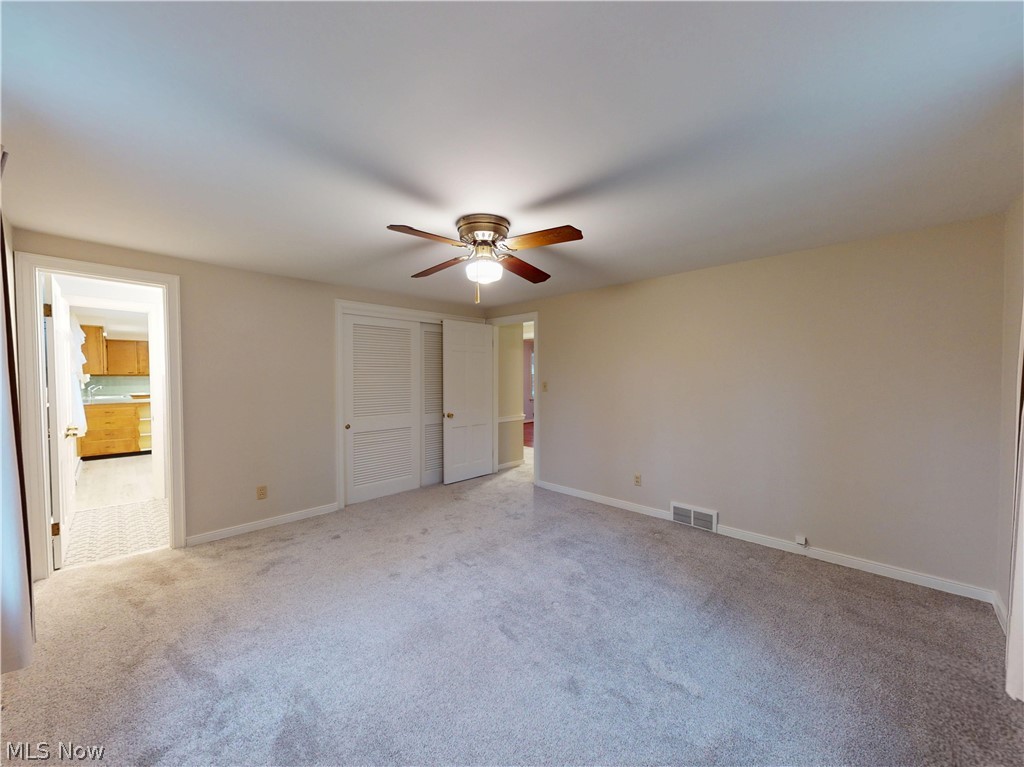 145 Overlook Road Painesville, OH 44077 - Photo 9 of 36 Unfurnished bedroom with light colored carpet, a closet, a ceiling fan, and connected bathroom