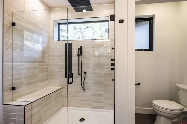 a bathroom with a granite countertop sink a toilet a mirror and window