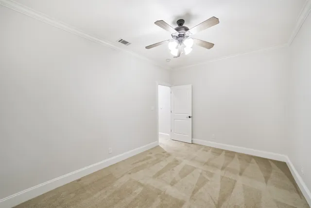 an empty room with a chandelier fan and windows