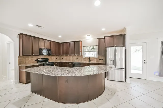 a large kitchen with stainless steel appliances granite countertop a stove a refrigerator a sink and a microwave