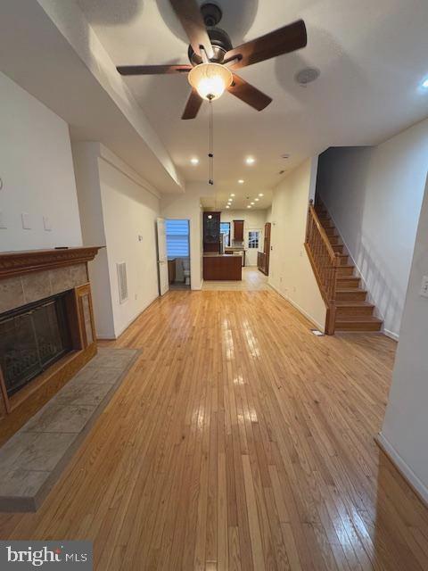 an empty room with wooden floor a ceiling fan a fireplace and windows