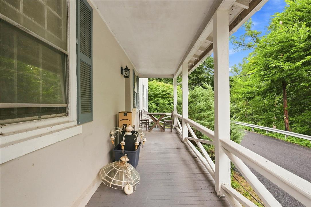 3408 Oak Hill Road Emmaus, PA 18049 - Photo 6 of 93 Wooden posts and railings frame a long covered porch overlooking a tree-lined driveway.