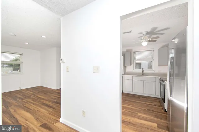 a view of a hallway with wooden floor and a bathroom