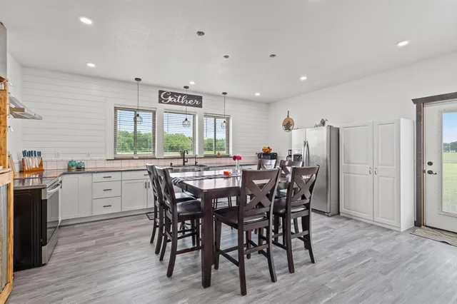 a kitchen with stainless steel appliances a table chairs sink and stove top oven