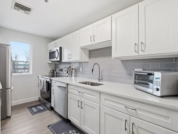 a kitchen with stainless steel appliances granite countertop white cabinets a sink and dishwasher