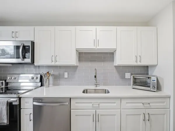 a kitchen with white cabinets and sink