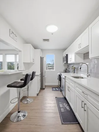 a kitchen with stainless steel appliances a sink cabinets and wooden floor