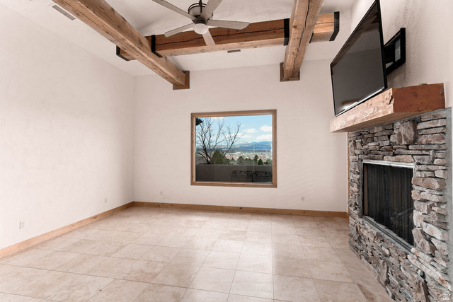 2464 East Granite Way St. George, UT 84790 - Photo 74 of 106 Unfurnished living room featuring a ceiling fan, beam ceiling, and a stone fireplace