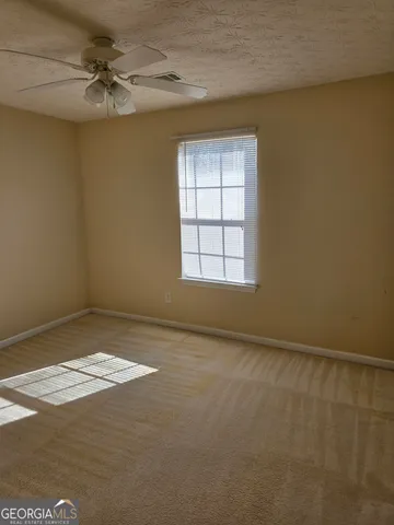 an empty room with windows and fan