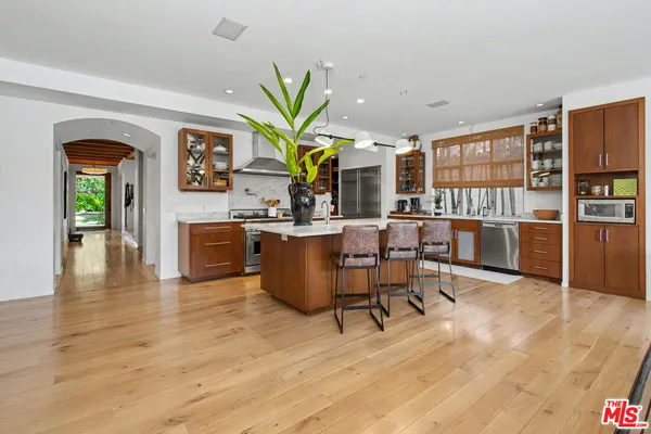 a kitchen with stainless steel appliances granite countertop a refrigerator a stove a sink dishwasher and white cabinets with wooden floor