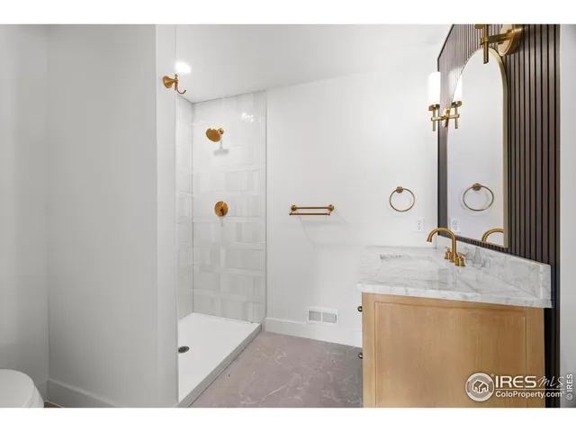a bathroom with a granite countertop sink a mirror and shower