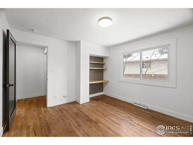 a view of an empty room with window and wooden floor