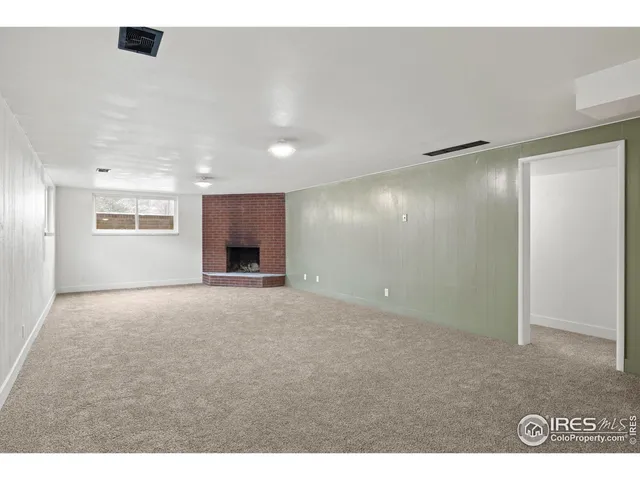 a view of an empty room with a fireplace and a window