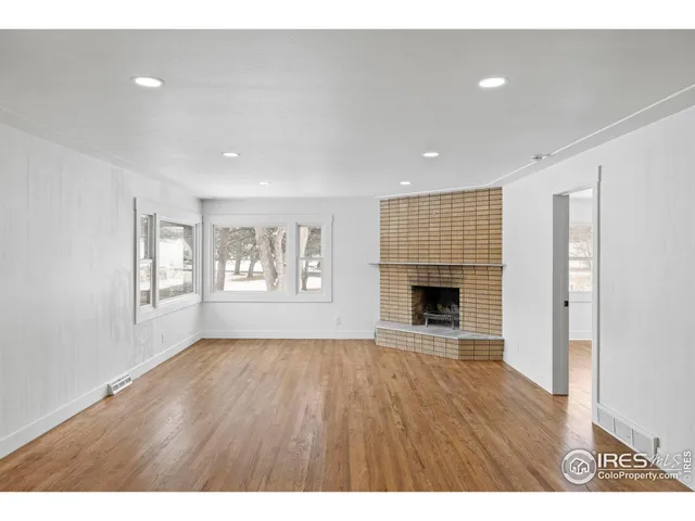 a view of an empty room with a window and fireplace