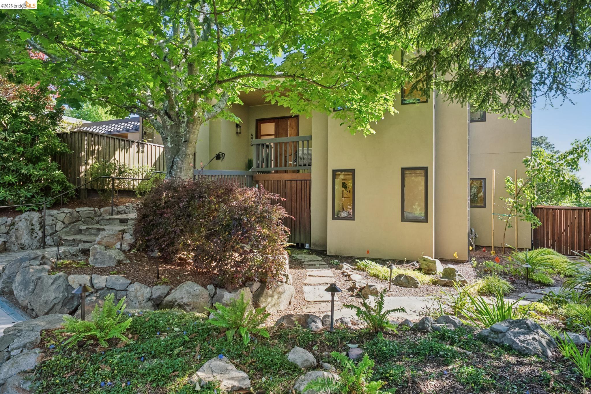 576 Vistamont Avenue Berkeley, CA 94708 - Photo 2 of 33 Multi-level exterior with a stucco finish, featuring a second-story balcony with wood railing, a stone staircase with metal handrails, and a flagstone pathway