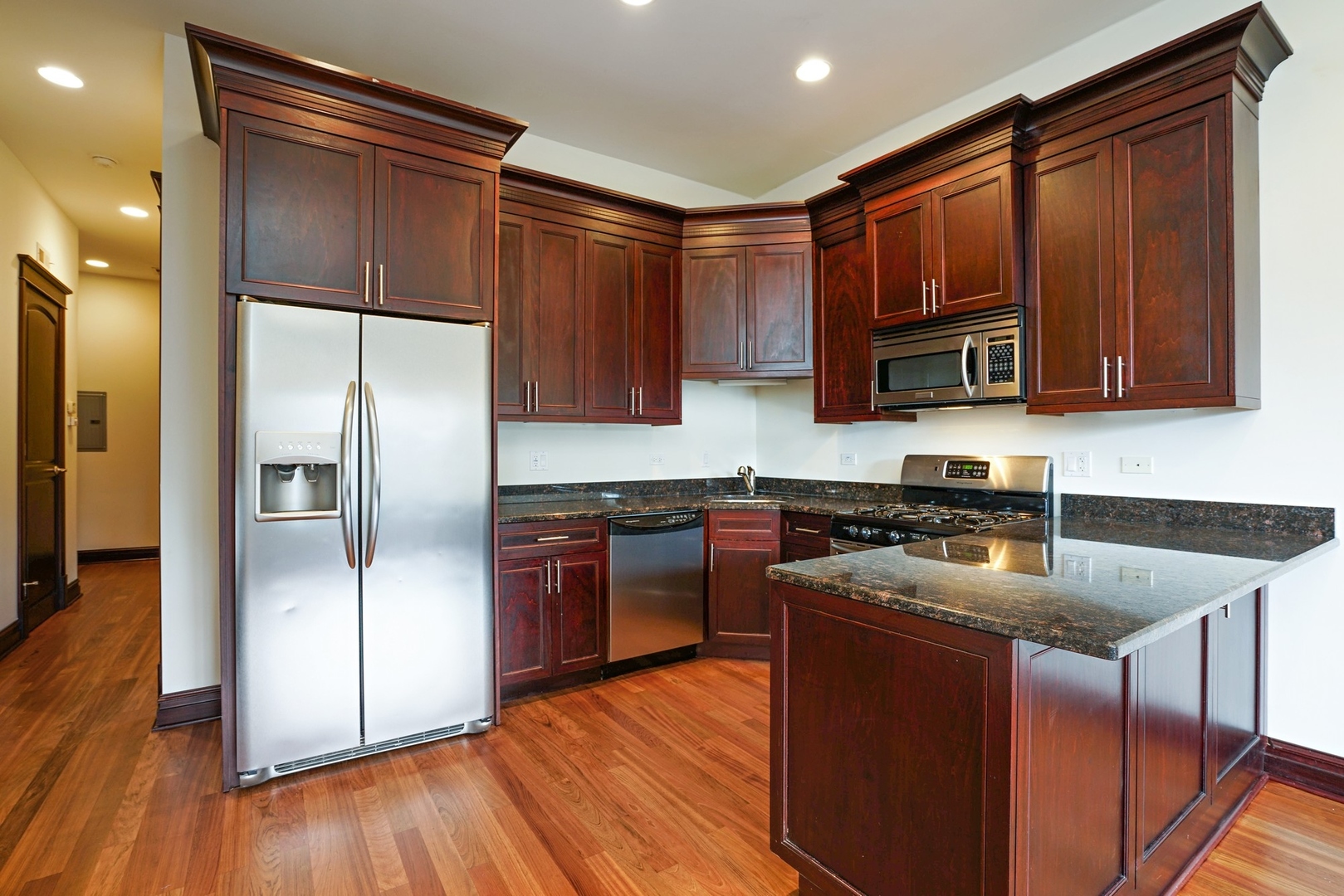 1416 West Superior Street, Unit 3F Chicago, IL 60642 - Photo 6 of 11 a kitchen with kitchen island granite countertop wooden floors stainless steel appliances a sink and a window