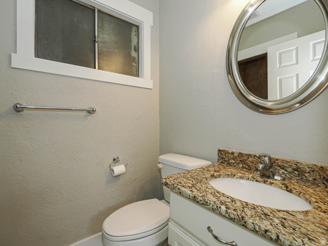154 East 3000th Street South Bountiful, UT 84010 - Photo 25 of 37 Powder room featuring a granite-style countertop, white vanity with cabinet storage, oval mirror, and a window with frosted glass