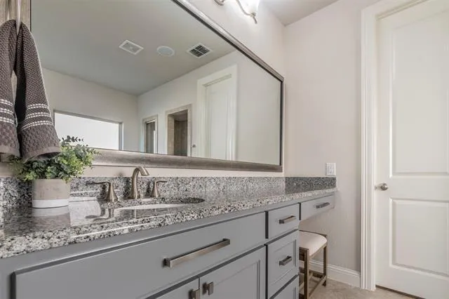 a bathroom with a granite countertop sink and a mirror