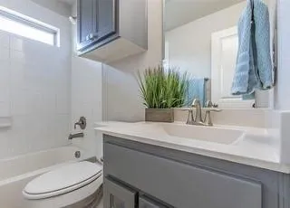 a bathroom with a granite countertop toilet sink and mirror