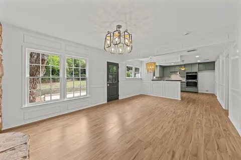 a view of an empty room with a window and wooden floor