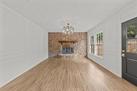 a view of an empty room with wooden floor fireplace and a window
