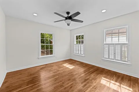 a view of an empty room with a window and wooden floor