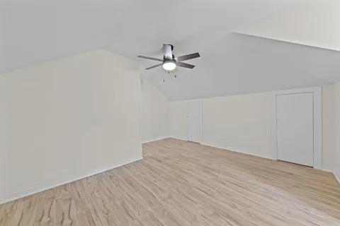 a view of a room with wooden floor and a ceiling fan