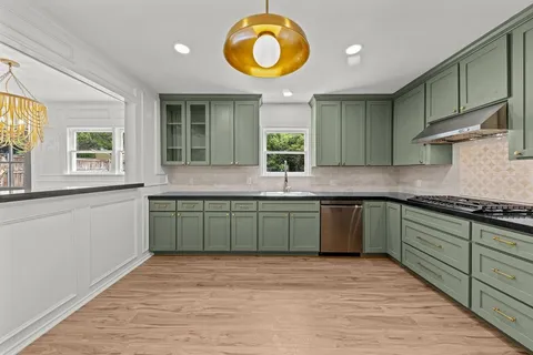 a kitchen with granite countertop a stove a sink and a wooden floors