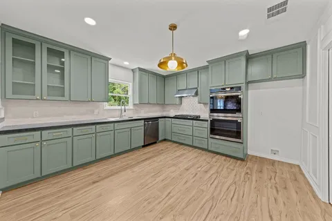a kitchen with stainless steel appliances granite countertop a sink cabinets and wooden floor