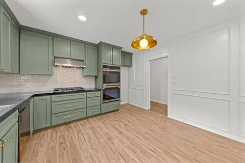 a kitchen with stainless steel appliances granite countertop a refrigerator a oven and a wooden floors