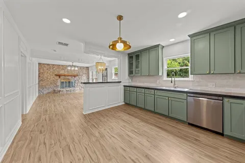 a kitchen with stainless steel appliances granite countertop a sink cabinets and wooden floor