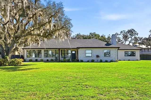 a view of a house with a big yard and large trees