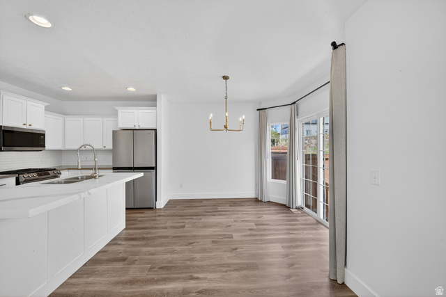 14771 Haddington Road Draper, UT 84020 - Photo 14 of 44 Open-concept kitchen and dining area featuring white cabinetry, stainless steel appliances, and wood-finish flooring
