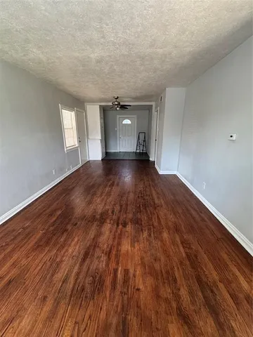 a view of an empty room with wooden floor and window