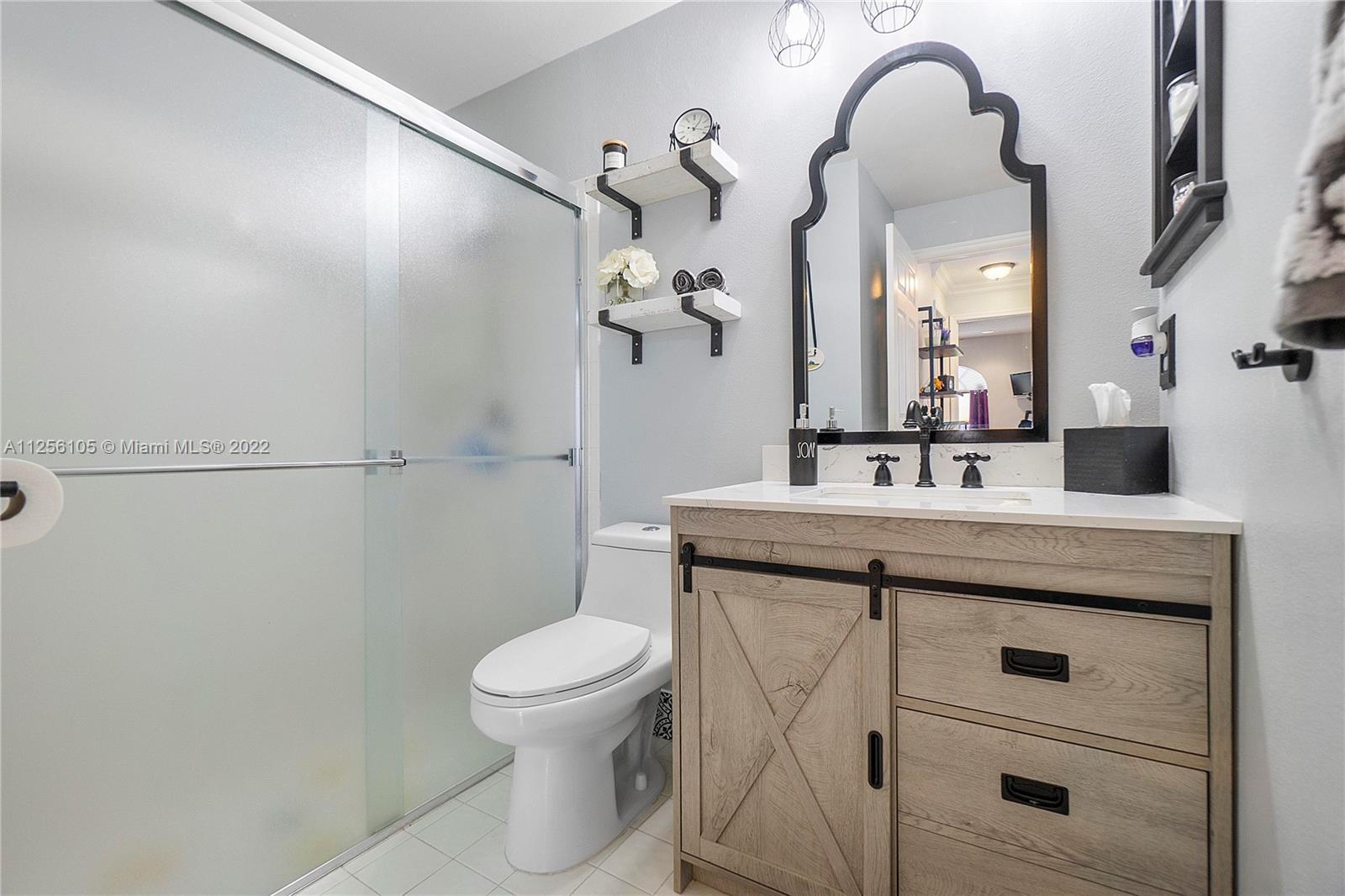 7677 Doubleton Drive Delray Beach, FL 33446 - Photo 17 of 42 a bathroom with a sink a toilet and a mirror
