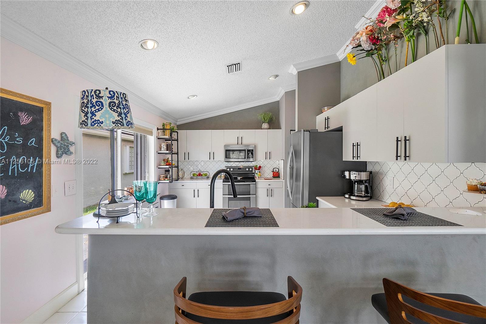 7677 Doubleton Drive Delray Beach, FL 33446 - Photo 30 of 42 a kitchen with a sink and a refrigerator