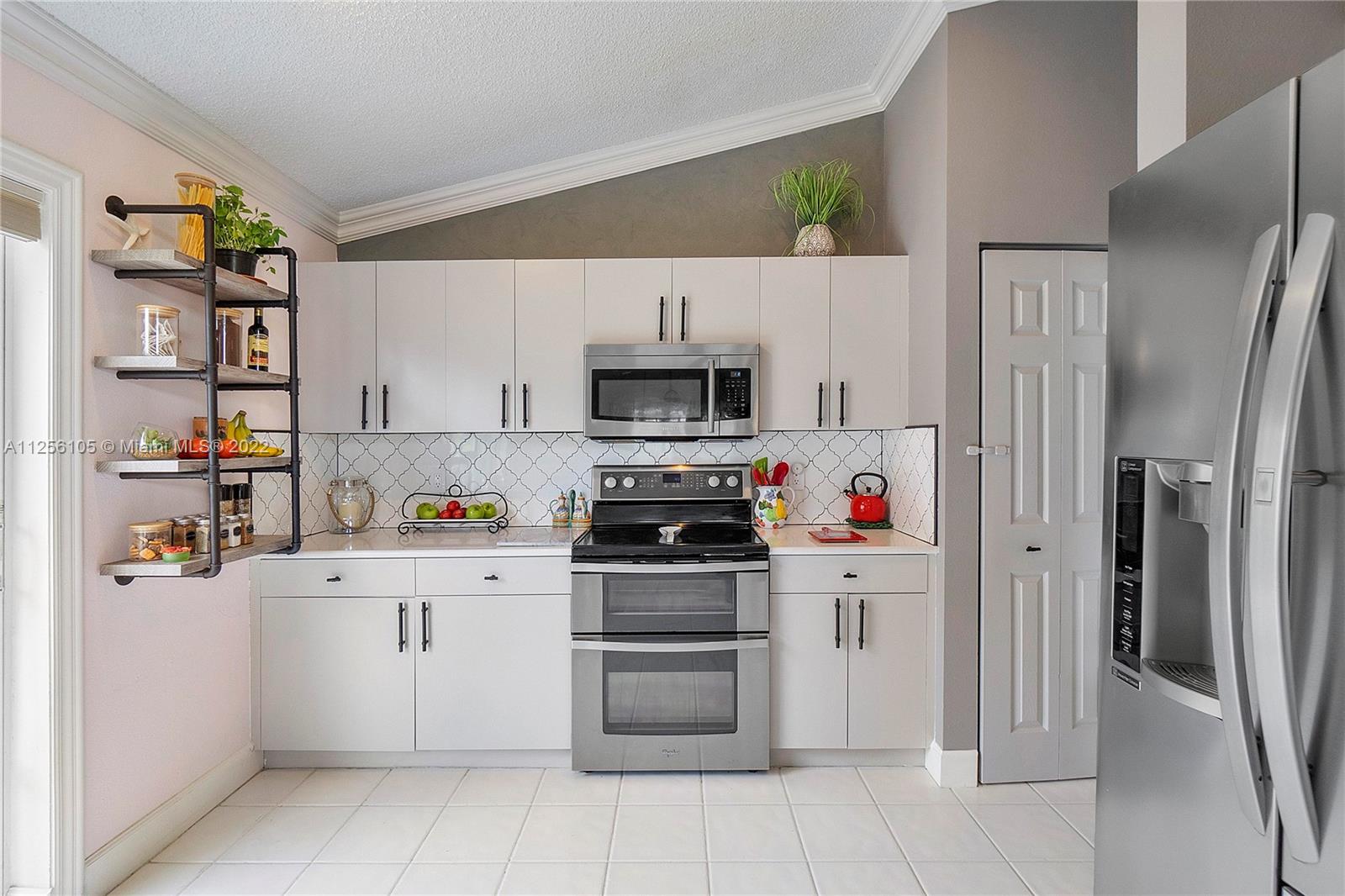 7677 Doubleton Drive Delray Beach, FL 33446 - Photo 32 of 42 a kitchen with stainless steel appliances a refrigerator and a stove top oven